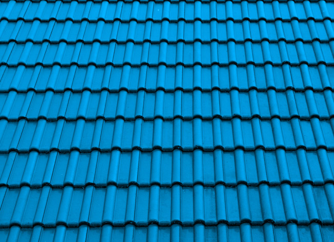 Fotografia de um telhado. As telhas estão pintadas de azul. 